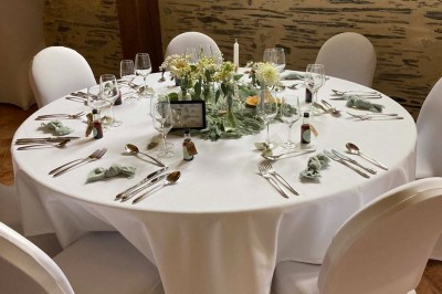 Chambre avec lit double, armoire en bois, canapé et tapis, murs en pierre et plafond avec poutres apparentes.