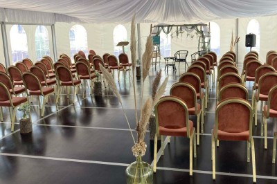 Chambre avec lit double, armoire en bois, canapé et tapis, murs en pierre et plafond avec poutres apparentes.