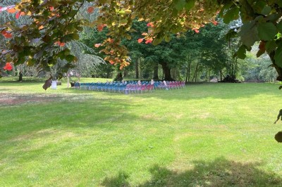 Chambre avec lit double, armoire en bois, canapé et tapis, murs en pierre et plafond avec poutres apparentes.