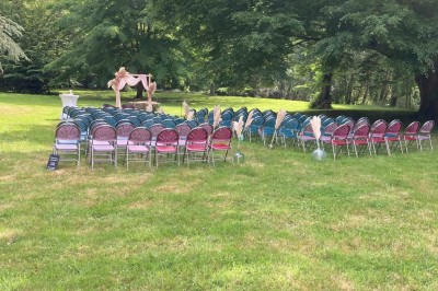 Chambre avec lit double, armoire en bois, canapé et tapis, murs en pierre et plafond avec poutres apparentes.