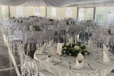 Chambre avec lit double, armoire en bois, canapé et tapis, murs en pierre et plafond avec poutres apparentes.