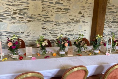 Chambre avec lit double, armoire en bois, canapé et tapis, murs en pierre et plafond avec poutres apparentes.