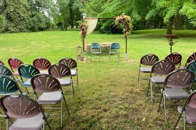 Chambre avec lit double, armoire en bois, canapé et tapis, murs en pierre et plafond avec poutres apparentes.