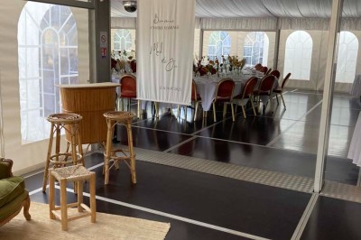 Chambre avec lit double, armoire en bois, canapé et tapis, murs en pierre et plafond avec poutres apparentes.