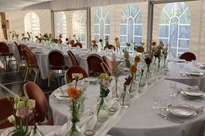 Chambre avec lit double, armoire en bois, canapé et tapis, murs en pierre et plafond avec poutres apparentes.