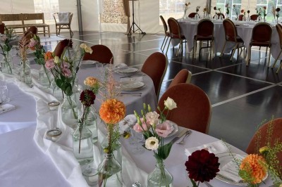Chambre avec lit double, armoire en bois, canapé et tapis, murs en pierre et plafond avec poutres apparentes.