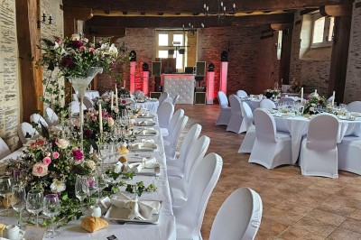Chambre avec lit double, armoire en bois, canapé et tapis, murs en pierre et plafond avec poutres apparentes.