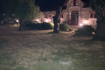 Groupe de personnes assises en cercle dans un jardin verdoyant, vu depuis une fenêtre d'un bâtiment en briques.