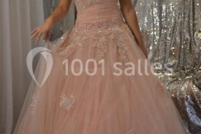 Deux femmes en robes traditionnelles violettes ornées de bijoux, posant devant un fond clair avec un fauteuil argenté.