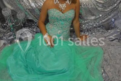 Deux femmes en robes traditionnelles violettes ornées de bijoux, posant devant un fond clair avec un fauteuil argenté.