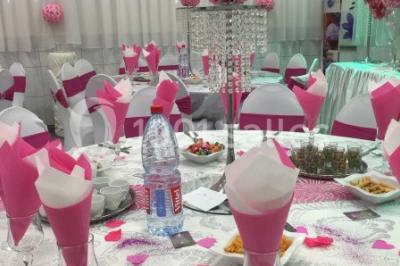 Deux femmes en robes traditionnelles violettes ornées de bijoux, posant devant un fond clair avec un fauteuil argenté.