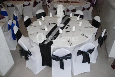 Deux femmes en robes traditionnelles violettes ornées de bijoux, posant devant un fond clair avec un fauteuil argenté.