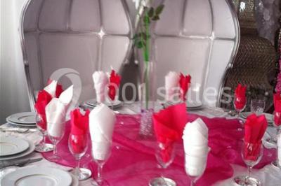 Deux femmes en robes traditionnelles violettes ornées de bijoux, posant devant un fond clair avec un fauteuil argenté.