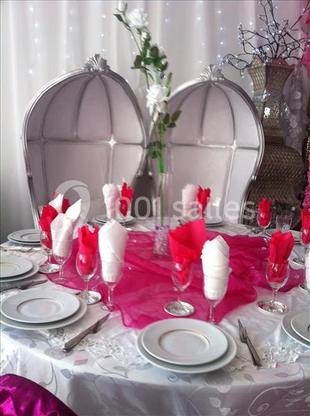 Table élégamment dressée avec nappes blanches, serviettes rouges et blanches, et deux chaises hautes argentées.