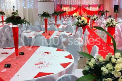 Deux femmes en robes traditionnelles violettes ornées de bijoux, posant devant un fond clair avec un fauteuil argenté.