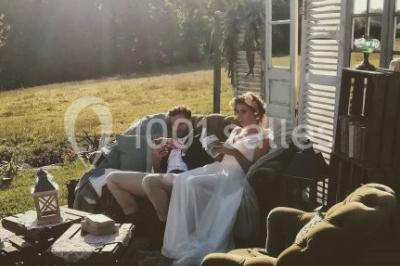 Un couple en tenue de mariage se regarde sous une pergola illuminée de guirlandes lumineuses.