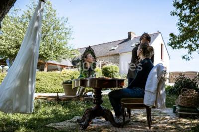Un couple en tenue de mariage se regarde sous une pergola illuminée de guirlandes lumineuses.