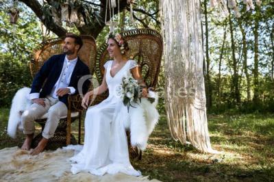 Un couple en tenue de mariage se regarde sous une pergola illuminée de guirlandes lumineuses.