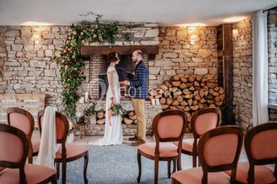Un couple en tenue de mariage se regarde sous une pergola illuminée de guirlandes lumineuses.