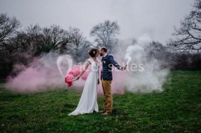 Un couple en tenue de mariage se regarde sous une pergola illuminée de guirlandes lumineuses.