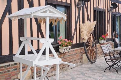 Terrasse extérieure avec tables dressées, parasols blancs, lampadaire et bâtiment à colombages en arrière-plan.