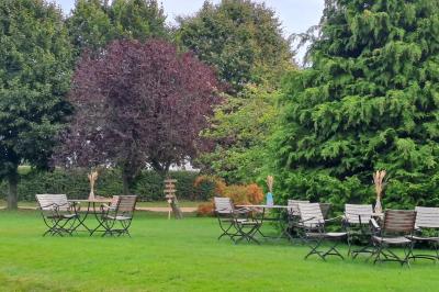 Terrasse extérieure avec tables dressées, parasols blancs, lampadaire et bâtiment à colombages en arrière-plan.
