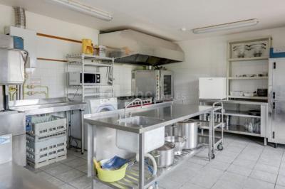 Terrasse extérieure avec tables dressées, parasols blancs, lampadaire et bâtiment à colombages en arrière-plan.