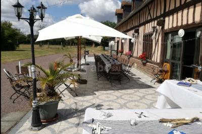 Terrasse extérieure avec tables dressées, parasols blancs, lampadaire et bâtiment à colombages en arrière-plan.