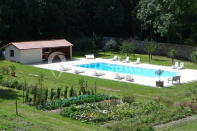 Chambre lumineuse avec un lit double, des rideaux fleuris, un lustre, des meubles classiques et des fenêtres donnant sur la…
